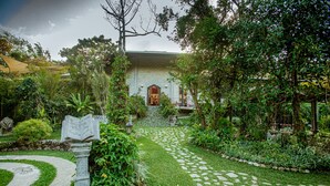 Un sendero en un jardín que lleva a un edificio con fachada de piedra y una entrada central.
