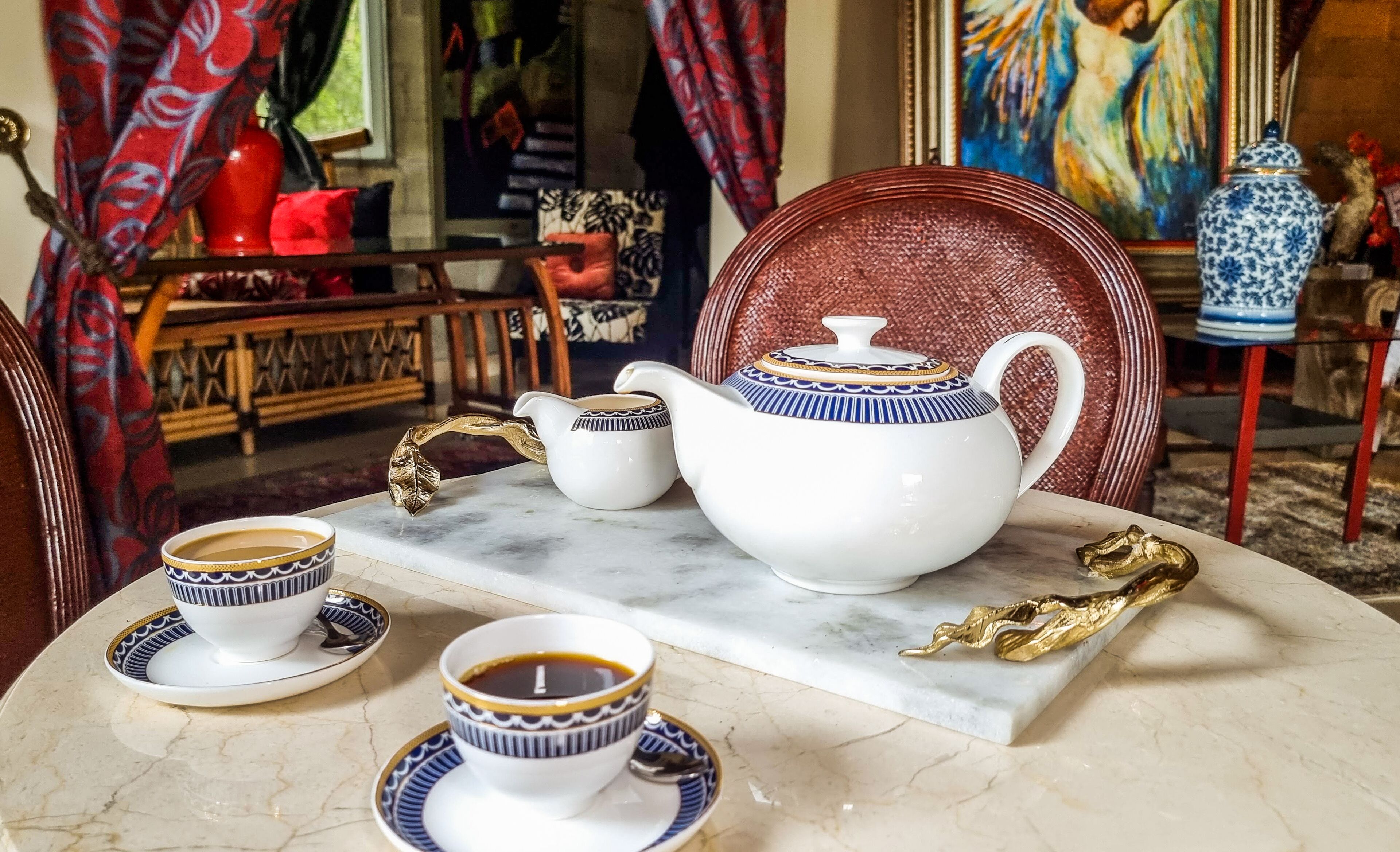 Un juego de té sobre una mesa de mármol con una hoja decorativa y un adorno dorado.