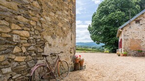 A stone building with a gravel driveway and a bicycle leaning against the wall.