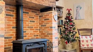 A cozy room with a brick fireplace, a Christmas tree, and a bicycle hanging on the wall.