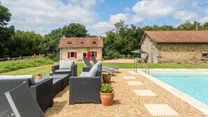 A poolside area with wicker furniture and a stone building in the background.