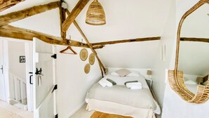 A bedroom with a bed, a hanging basket, a mirror, and a woven rug.