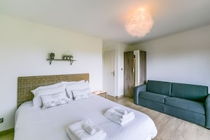 A bedroom with a bed, bedside tables, a green sofa, and a hanging light fixture. - Chateau Paradis - Twentyeight Bedroom Castle, Sleeps 91 (Benest)