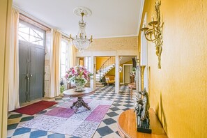 A foyer with a checkered floor, a chandelier, a table with a floral arrangement, and a staircase in the background. - Chateau Paradis - Twentyeight Bedroom Castle, Sleeps 91 (Benest)