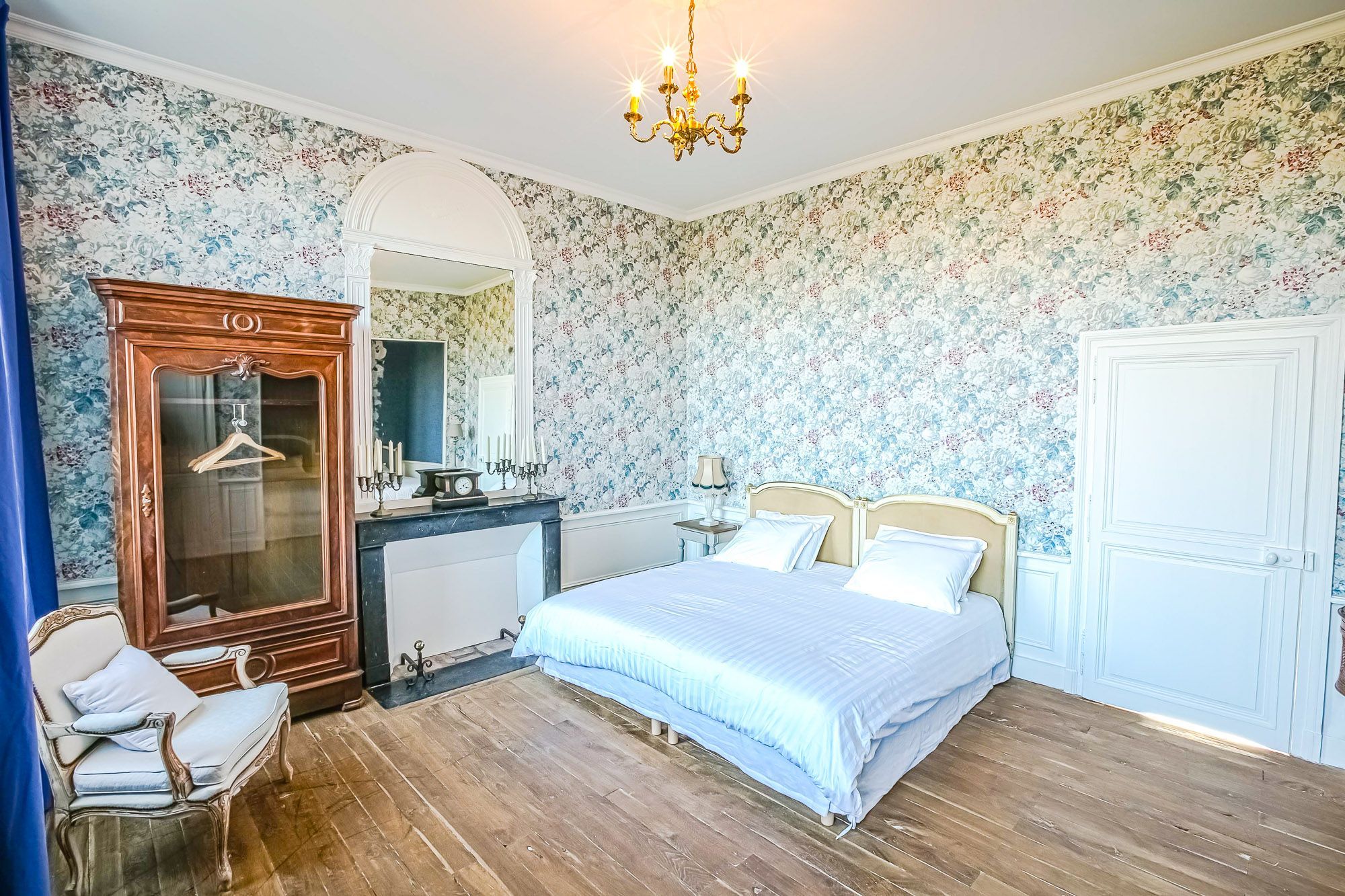 Une chambre à coucher avec un lit, une commode, une chaise et un miroir.