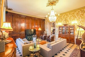 A traditional living room with a fireplace, a television, and a bookshelf. - Chateau Paradis - Twentyeight Bedroom Castle, Sleeps 91 (Benest)