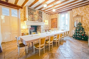 A dining area with a long table, chairs, a fireplace, and a decorated Christmas tree. - Chateau Paradis - Twentyeight Bedroom Castle, Sleeps 91 (Benest)