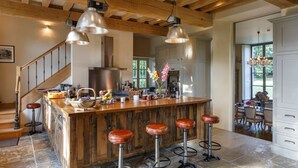 A spacious kitchen with a central island, wooden beams, and pendant lighting. - Chateau Quatre Saisons (Domjean)