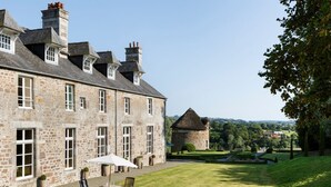 A stone building with a large patio area, outdoor seating, and a view of the surrounding landscape. - Chateau Quatre Saisons (Domjean)