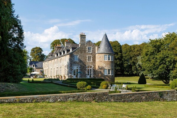 A large stone building with a turret and a well-maintained lawn. - Chateau Quatre Saisons (Domjean)