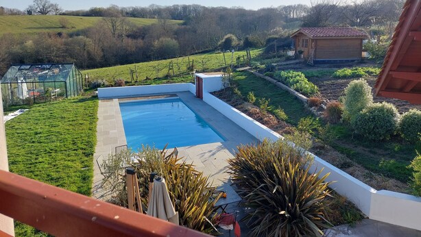 A rooftop pool with a view of a vineyard and a wooden house in the background. - Beautiful, quiet Basque villa with heated pool (Ahetze)