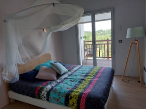 Relax in this serene bedroom with a large bed, a cozy canopy, and a sliding door leading to a balcony.