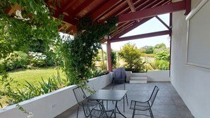 An outdoor patio with a table and chairs, surrounded by greenery and a view of the landscape. - Beautiful, quiet Basque villa with heated pool (Ahetze)