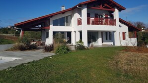 A two-story house with a red roof and white walls, featuring a balcony with red railings. - Beautiful, quiet Basque villa with heated pool (Ahetze)
