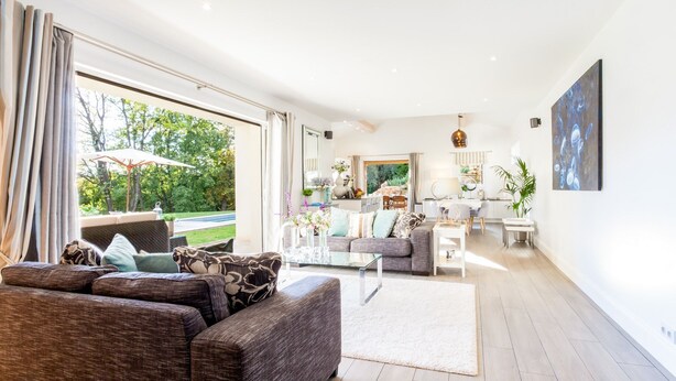 A spacious living area with a large sofa, a dining table, and a kitchen in the background.