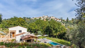 A villa with a pool, stone architecture, and a view of a hilltop town.