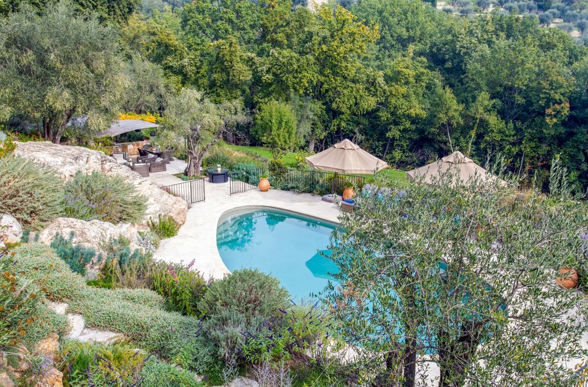Un jardin aménagé à l’arrière de la maison, avec une piscine, entouré d’arbres et d’arbustes.