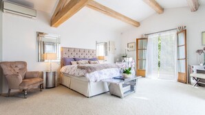 Een slaapkamer met een bed, nachtkastje, lamp, stoel en een groot raam.