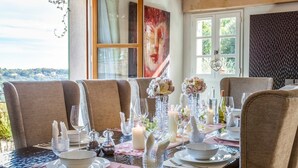 Een eettafel gedekt voor vier personen, met glanzend servies, kaarsen en een bloemstuk in het midden.