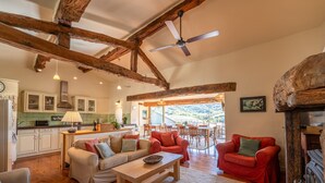 A spacious living area with a wooden ceiling, a kitchen with green tiles, and a dining area with a view. - Le Jardin Secret - Four Bedroom Villa, Sleeps 8 (Laurac)