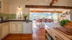 A kitchen with a central island, wooden cabinets, and a view of the outdoors. - Le Jardin Secret - Four Bedroom Villa, Sleeps 8 (Laurac)
