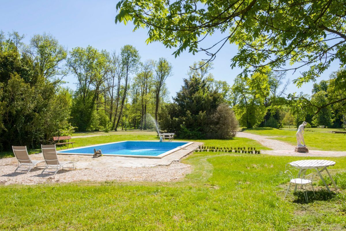 A backyard with a swimming pool, outdoor seating, and a statue.