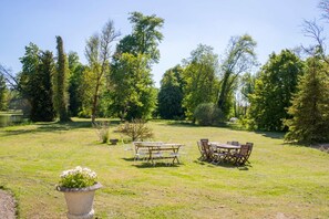 An outdoor dining area with a table and chairs, surrounded by trees and a grassy lawn. - Chateau Des Temps - Ten Bedroom Castle, Sleeps 20 (Pleurs)