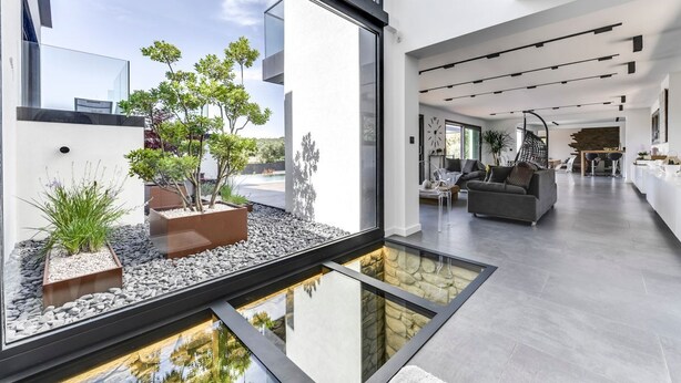 Un intérieur moderne avec un élément décoratif aquatique à fond de verre, un canapé gris et un design minimaliste.