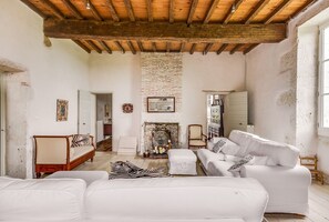 A rustic living room with exposed wooden beams, a brick fireplace, white sofas, and a zebra-patterned rug. - La Maison Des Moines (Loubès-Bernac)