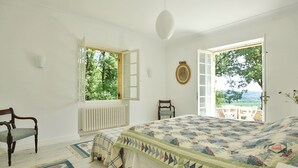 Une chambre avec un grand lit, une chaise, un radiateur et une vue sur l’extérieur.