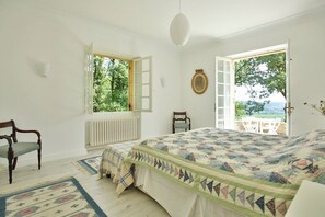 Une chambre avec un grand lit, une chaise, un radiateur et une vue sur l’extérieur.