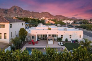 Une maison moderne dotée d’une piscine, de mobilier de jardin et offrant une vue sur les montagnes.