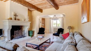A living room with a fireplace, a sofa, a coffee table, and a chandelier. - Mas Des Collines - Six Bedroom Villa, Sleeps 12 (Saignon)