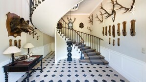 Un magnifique escalier à rampe, dont le design est en spirale, et qui est orné de têtes et de bois de cerf fixés aux murs.