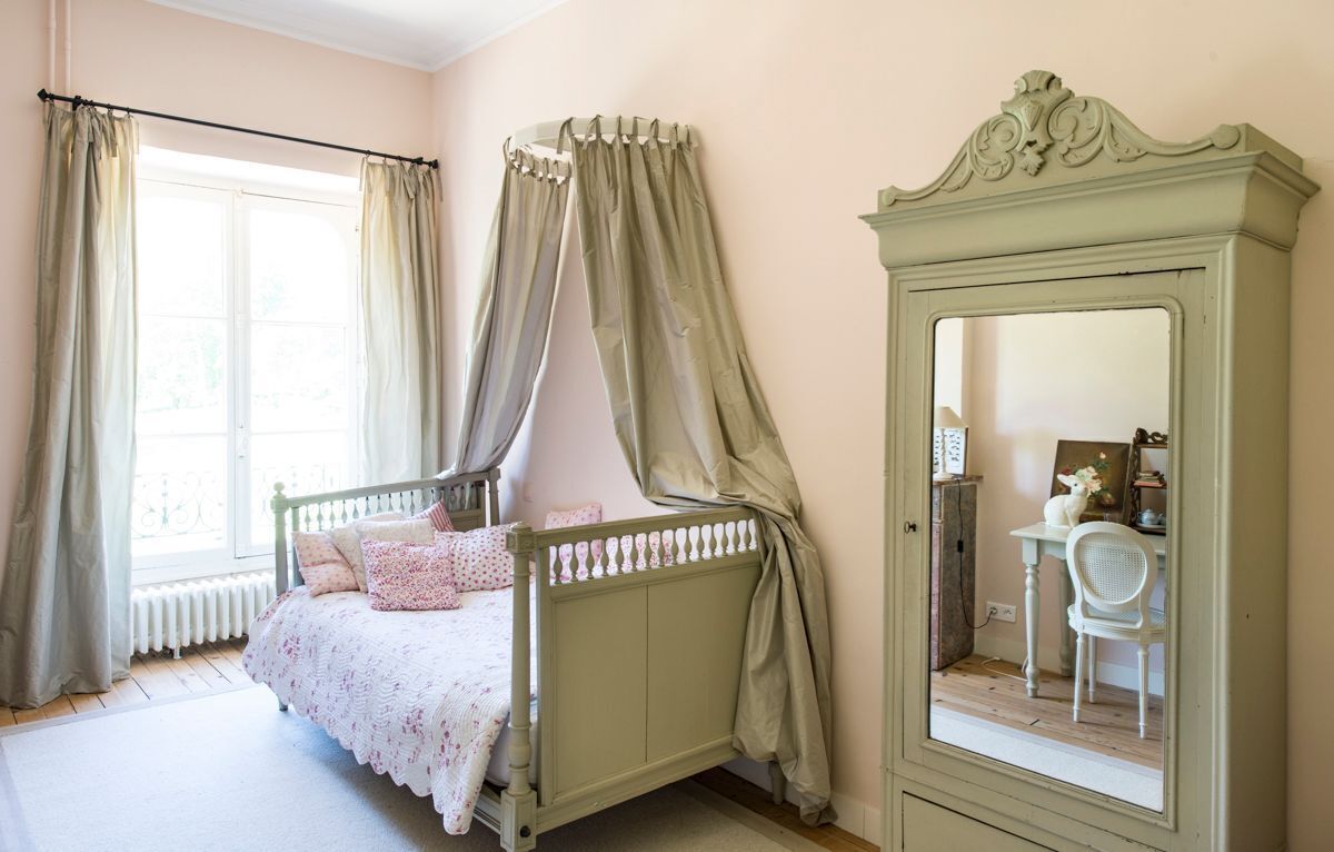 A bedroom with a bed, a mirror, and a chair.