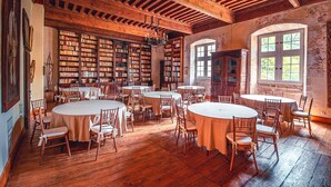 Une bibliothèque avec des étagères en bois, des tables rondes et des chaises.