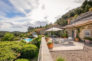A stone building with a patio, outdoor seating, and a pool. - Les Rochers - Five Bedroom Villa, Sleeps 10 (Les Baux de Provence)