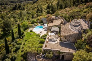An aerial view of a villa with a swimming pool, stone architecture, and surrounding greenery. - Les Rochers - Five Bedroom Villa, Sleeps 10 (Les Baux de Provence)