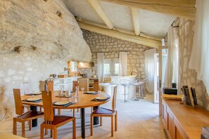 A rustic stone interior with a wooden dining table set for four, a bar area, and a stone wall. - Les Rochers - Five Bedroom Villa, Sleeps 10 (Les Baux de Provence)
