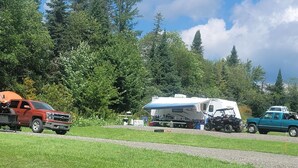 Ein Campingplatz mit einem Wohnwagen, einem roten Lastwagen und einem grünen Lastwagen.