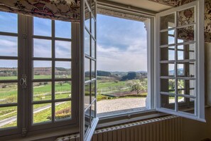 A room with a large window offering a view of a rural landscape. - Manoir Des Chasseurs (Saint-Prix)