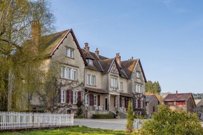 A traditional European-style building with multiple windows and a white picket fence. - Manoir Des Chasseurs (Saint-Prix)