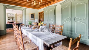 Una sala da pranzo con un lungo tavolo apparecchiato per un pasto, sedie di legno e un lampadario.