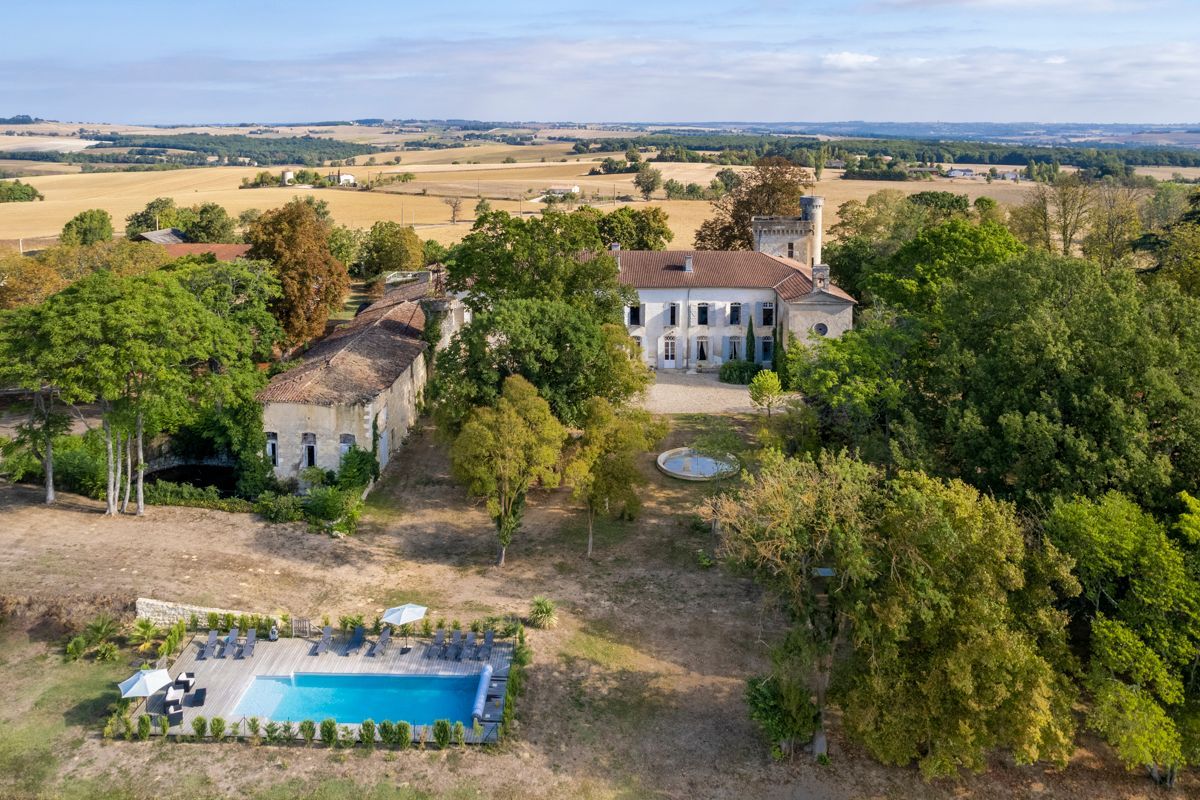 Un vaste domaine comprenant une piscine, un bâtiment principal et des champs environnants.