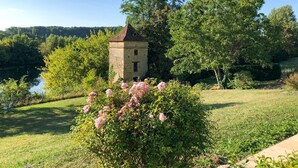 Ein steinerner Turm, umgeben von üppiger Vegetation und blauem Himmel.