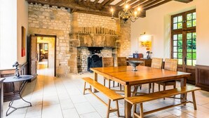 A rustic dining area with a stone fireplace, wooden beams, and a chandelier. - Manoir 1731 - Six Bedroom Villa, Sleeps 12 (Carlux)
