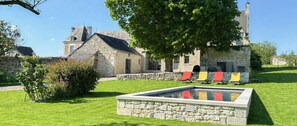 A stone building with a swimming pool and outdoor seating.