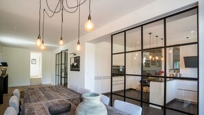 Une cuisine moderne avec des armoires blanches, un grand îlot central et des luminaires suspendus.