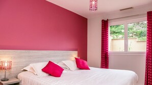 Ein Schlafzimmer mit einem großen Bett, zwei Nachttischen und einem Fenster mit Vorhängen.