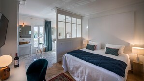 A hotel room with a bed, bedside table, lamp, and a view of the bathroom and dining area. - Chateau Grand Cru - Five Bedroom Castle, Sleeps 10 (Saint-Emilion)
